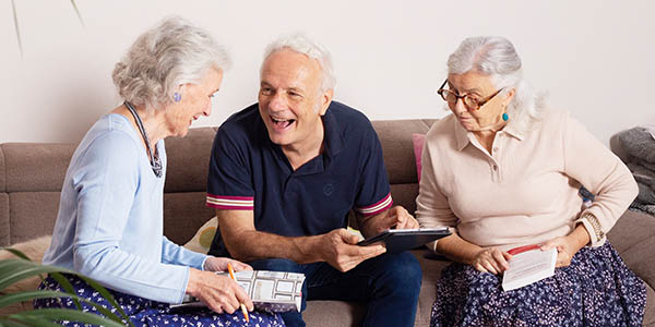 Trois personnes âgées rigolent et jouent ensemble dans le salon