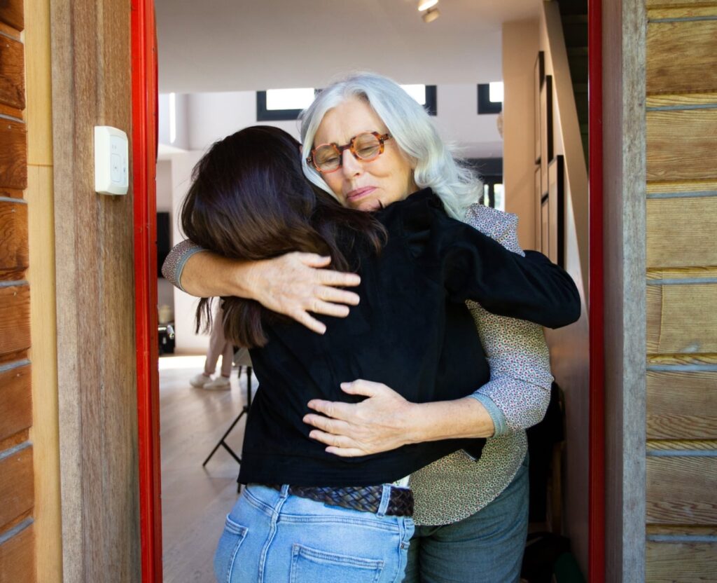 Une personne âgée prend dans ses bras sa petite fille venue lui rendre visite