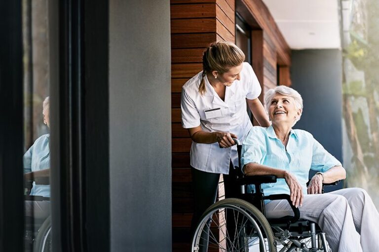 Dossier EHPAD : Une personne âgée, nouvellement admise en EHPAD, sur son fauteuil roulant accompagnée d'une infirmière.