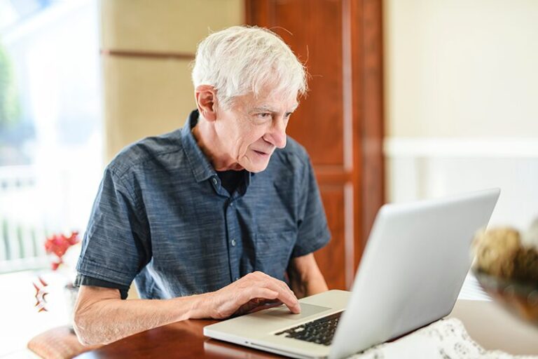 Un homme âgé utilisant un ordinateur portable pour se renseigner sur l’ERPD (État Prévisionnel des Recettes et des Dépenses).
