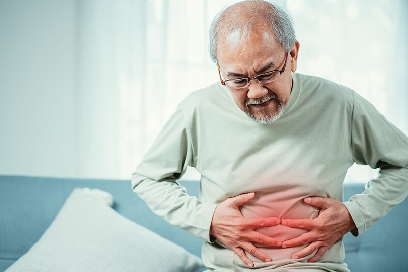 Une personne âgée souffrant de la maladie de Crohn qui se tient le ventre.