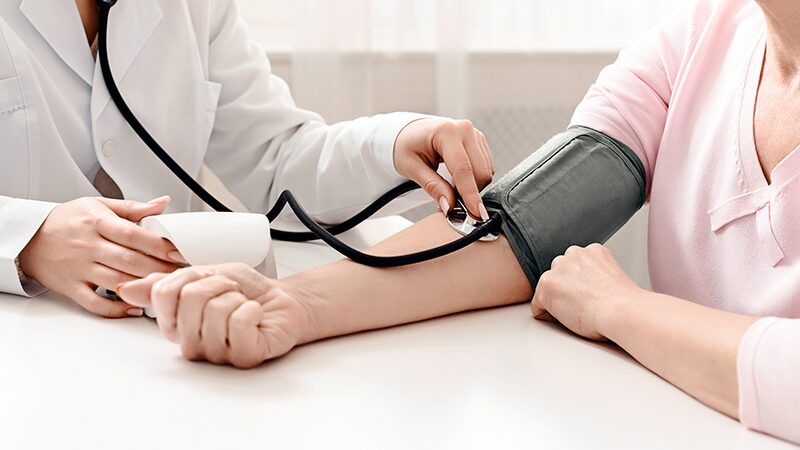 Professionnel de santé mesurant la tension d’une patiente lors d’un suivi médical pouvant inclure l’analyse du taux CRP et des marqueurs inflammatoires.
