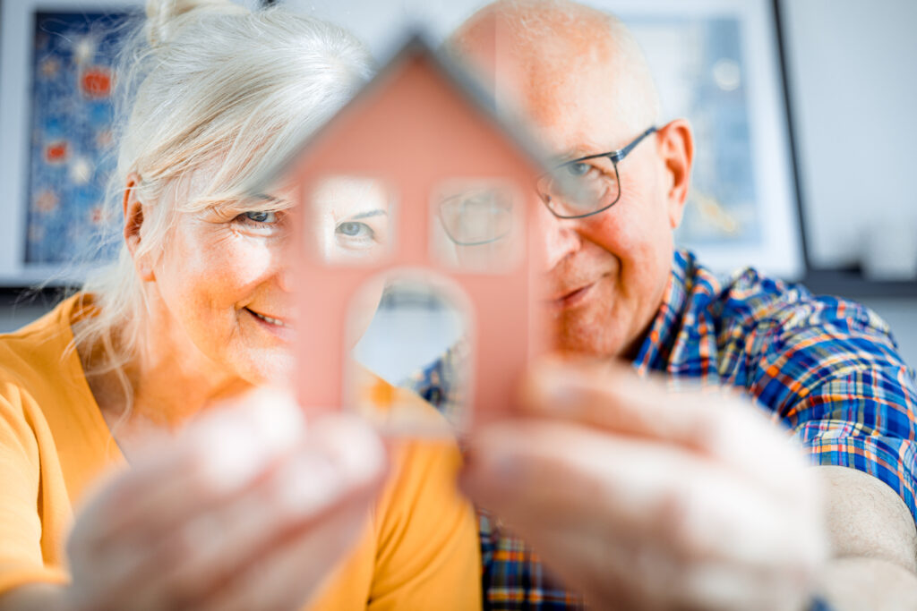 Un couple de personnes âgées tient et regarde à travers une maison