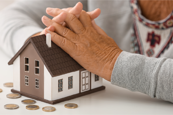 Une dame pose ses mains sur une maison miniature pour calculer l'aide sociale à l'hébergement