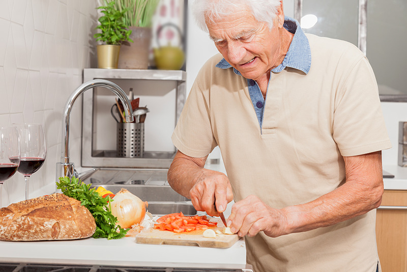 Dénutrition personne âgée : Un homme âgée de 70 ans prépare sa salade pour maintenir son équilibre nutritionnel.