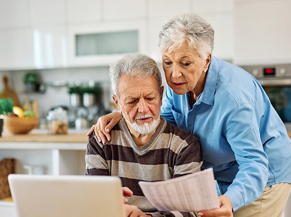 Un couple de personnes âgées, dans la cuisine, se renseignant sur la donation aux derniers vivants sur leur ordinateur.