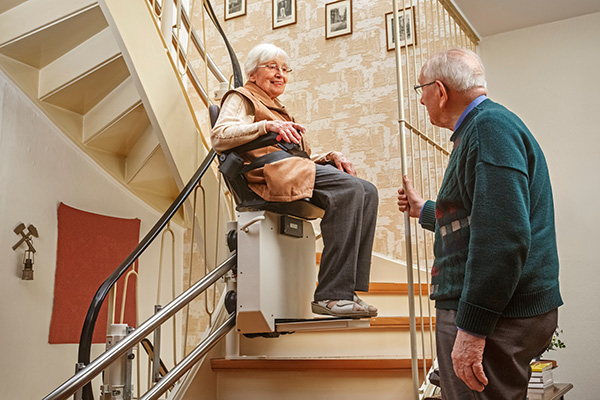 Un couple de personne âgée dans leur maison avec un monte-escalier