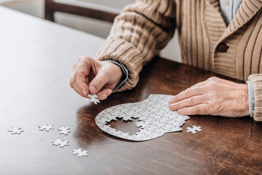 Main de seniors en train de faire un puzzle pour prévenir la maladie de pick.