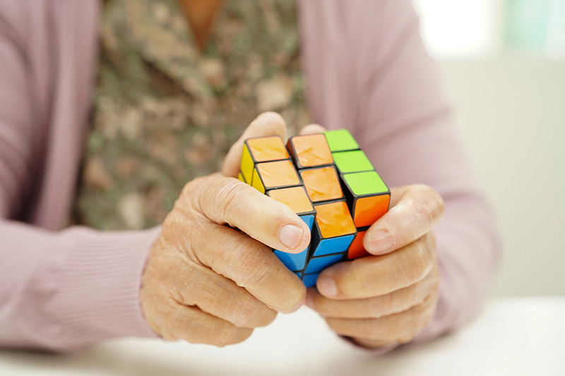 Montessori personne âgée : mains d'une personne âgée qui essaye de résoudre le Rubik's Cube