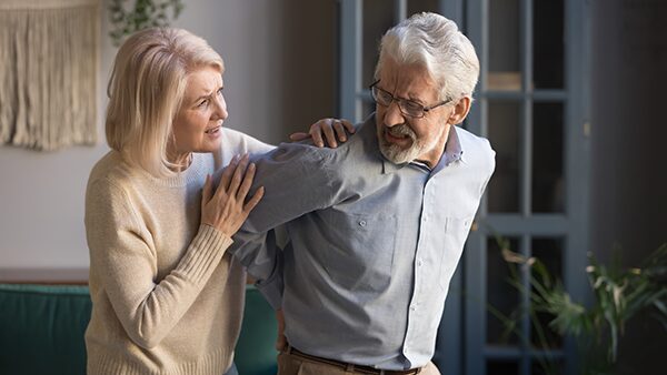 Un senior souffrant d'ostéopénie accompagner de sa femme qui l'épaule.
