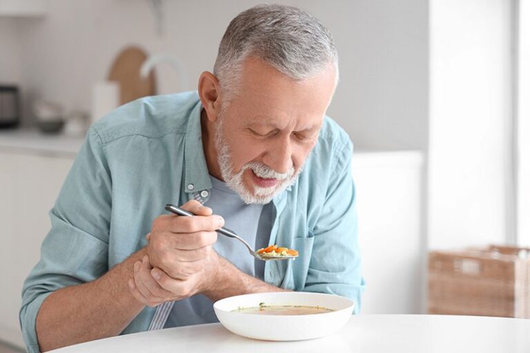 Une personne âgée atteinte de Parkinson mange une soupe adaptée pour éviter l'avancement de la maladie.