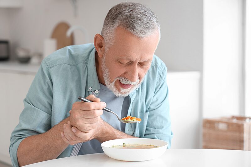Une personne âgée atteinte de Parkinson mange une soupe adaptée pour éviter l'avancement de la maladie.
